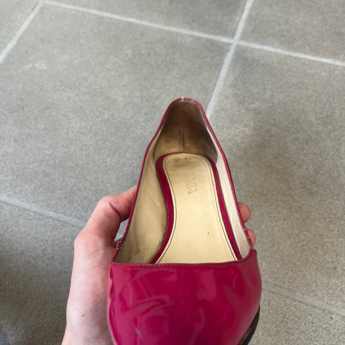 Prada 2000's Patent Leather Magenta Kitten Heels are made in Italy from magenta patent leather with a beige interior and sole, featuring a gold-tone metal Prada logo on the bottom and Prada branding on the insole. They come with the original box and two dust bags; the bottom and heel tip have been professionally repaired.