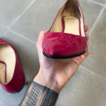 Prada 2000's Patent Leather Magenta Kitten Heels are made in Italy from magenta patent leather with a beige interior and sole, featuring a gold-tone metal Prada logo on the bottom and Prada branding on the insole. They come with the original box and two dust bags; the bottom and heel tip have been professionally repaired.
