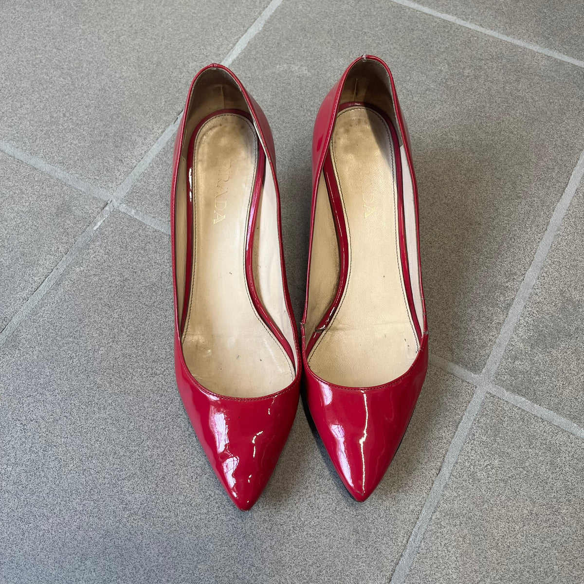 Prada 2000's Patent Leather Magenta Kitten Heels are made in Italy from magenta patent leather with a beige interior and sole, featuring a gold-tone metal Prada logo on the bottom and Prada branding on the insole. They come with the original box and two dust bags; the bottom and heel tip have been professionally repaired.