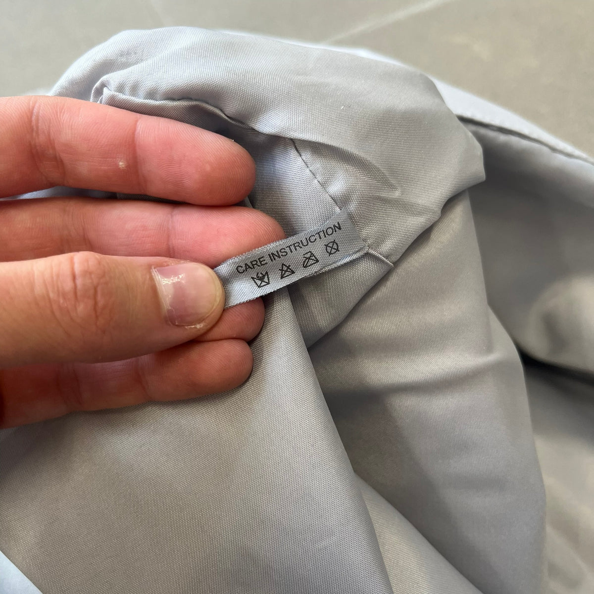 Prada 2012 Luna Rossa Drawstring Sling Bag is a light gray, almost silvery sling bag made as a gift-with-purchase for the Luna Rossa fragrance. It features a red rubber stripe at the bottom with white "Prada" and "Luna Rossa" text, and Prada branding on the drawstring toggle.