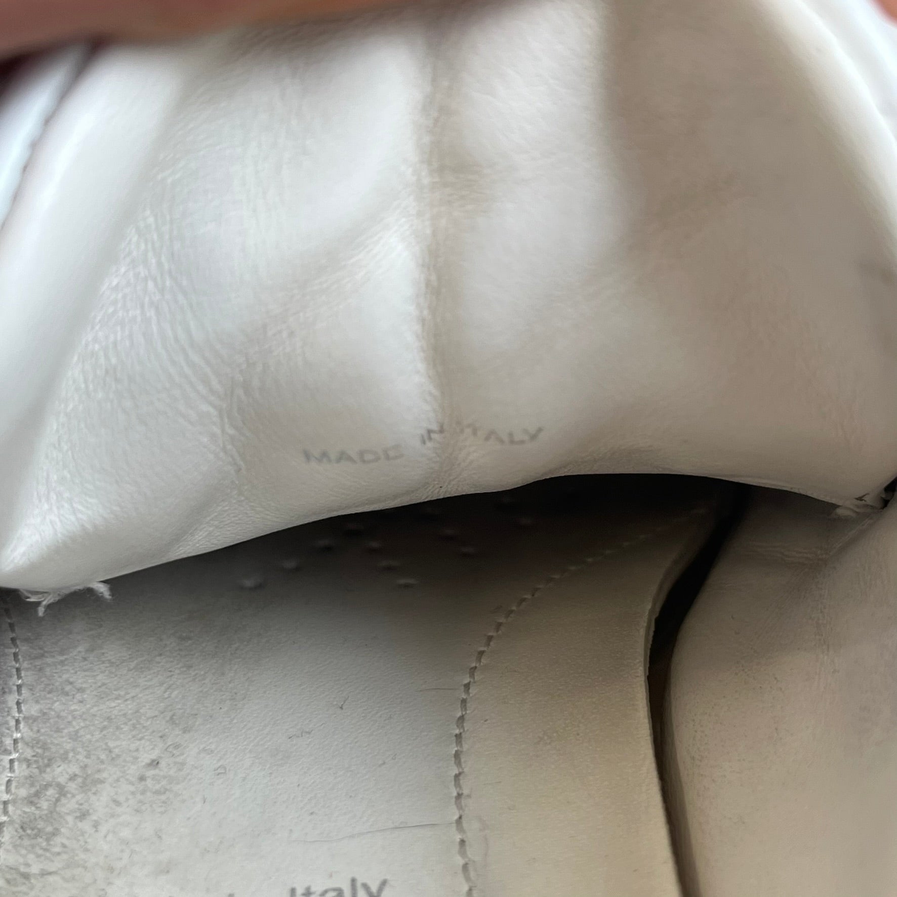 Prada Brushed Leather 2022 White Sneakers feature a classic low-top silhouette crafted from smooth white brushed leather. The outer sides are detailed with Prada's iconic enamel triangle logo plaques in white and silver-tone metal. Made in Italy.