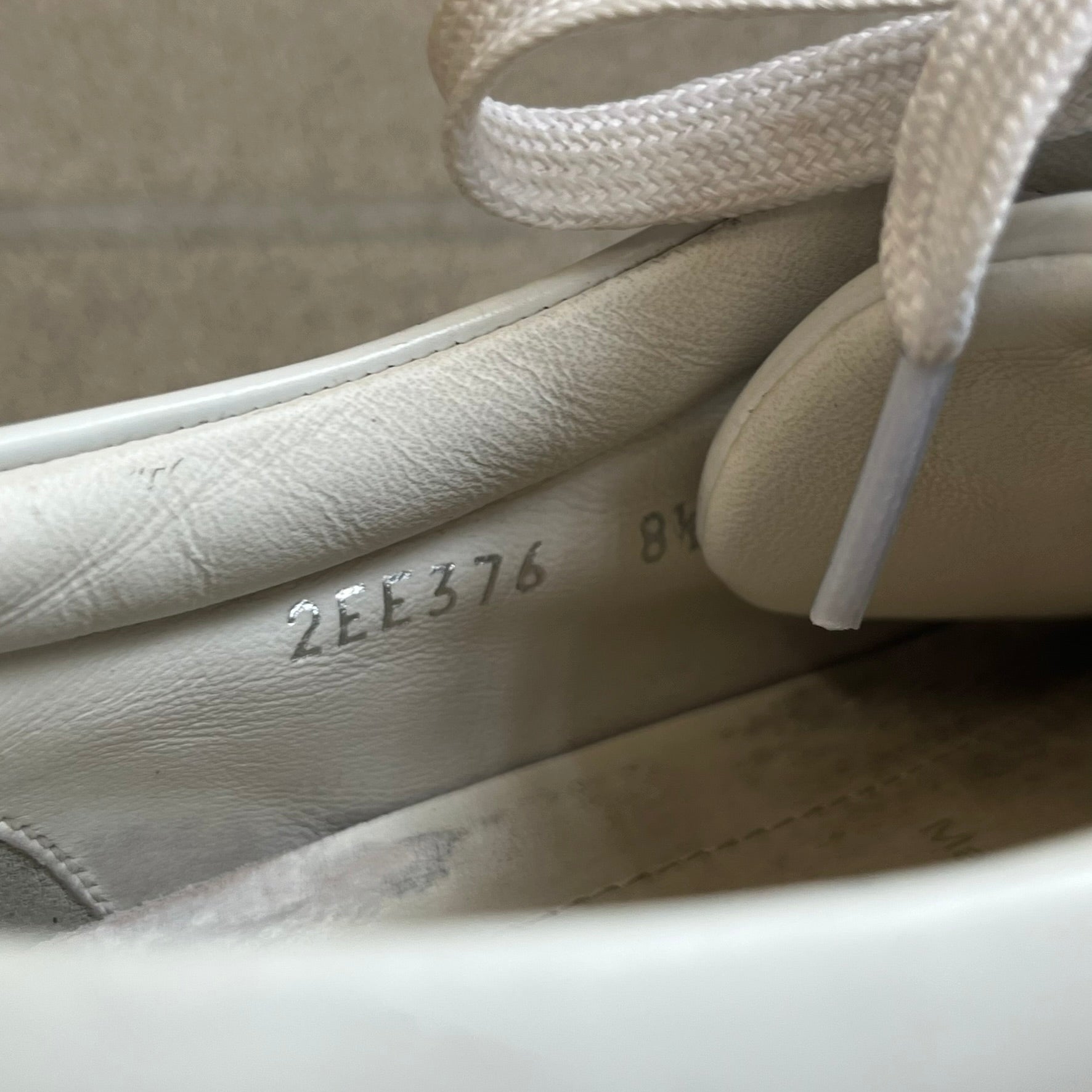 Prada Brushed Leather 2022 White Sneakers feature a classic low-top silhouette crafted from smooth white brushed leather. The outer sides are detailed with Prada's iconic enamel triangle logo plaques in white and silver-tone metal. Made in Italy.