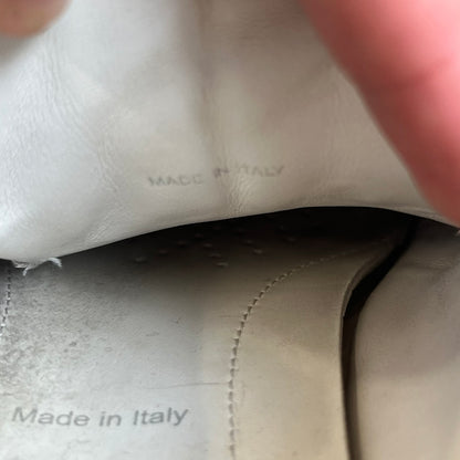 Prada Brushed Leather 2022 White Sneakers feature a classic low-top silhouette crafted from smooth white brushed leather. The outer sides are detailed with Prada's iconic enamel triangle logo plaques in white and silver-tone metal. Made in Italy.