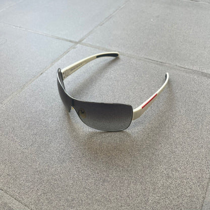 Prada Linea Rossa SPS57G White Sunglasses are shield-style sunglasses featuring a single dark wraparound lens and white arms. One temple is finished with the signature red Prada Linea Rossa logo insert, while the nose pads feature subtle Prada branding. Made in Italy, the sunglasses are lightweight sporty design&nbsp;and they come complete with the original Prada case.