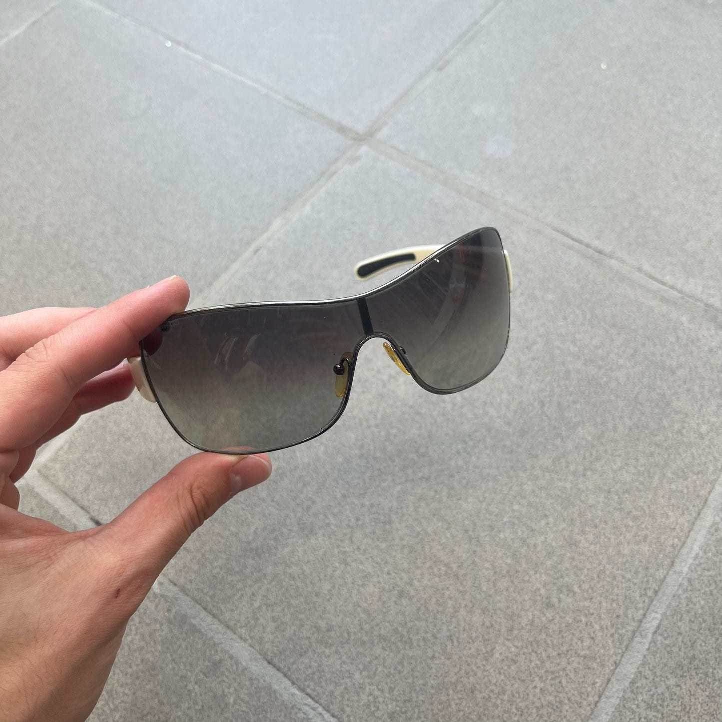 Prada Linea Rossa SPS57G White Sunglasses are shield-style sunglasses featuring a single dark wraparound lens and white arms. One temple is finished with the signature red Prada Linea Rossa logo insert, while the nose pads feature subtle Prada branding. Made in Italy, the sunglasses are lightweight sporty design&nbsp;and they come complete with the original Prada case.