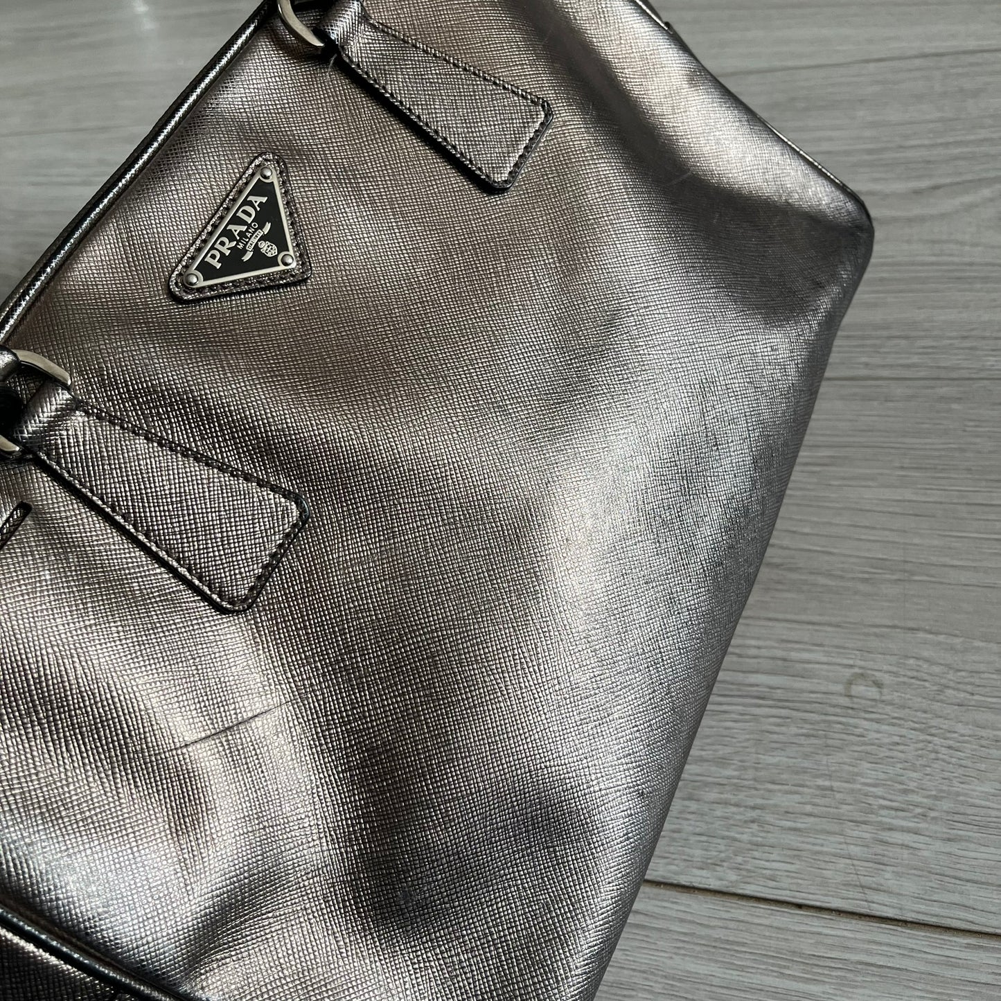 Vintage Prada Metallic Saffiano Bauletto Bag crafted from metallic gold saffiano leather embodies vintage elegance and modern luxury. Detailed with gold-tone hardware, dual handles, and original accessories, it’s a testament to Prada’s enduring craftsmanship. A collector’s piece made to shine on any occasion.
