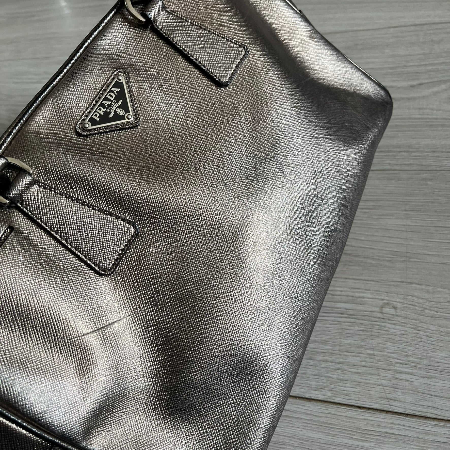 Vintage Prada Metallic Saffiano Bauletto Bag crafted from metallic gold saffiano leather embodies vintage elegance and modern luxury. Detailed with gold-tone hardware, dual handles, and original accessories, it’s a testament to Prada’s enduring craftsmanship. A collector’s piece made to shine on any occasion.