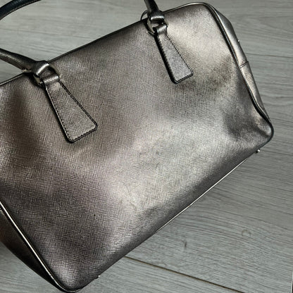 Vintage Prada Metallic Saffiano Bauletto Bag crafted from metallic gold saffiano leather embodies vintage elegance and modern luxury. Detailed with gold-tone hardware, dual handles, and original accessories, it’s a testament to Prada’s enduring craftsmanship. A collector’s piece made to shine on any occasion.