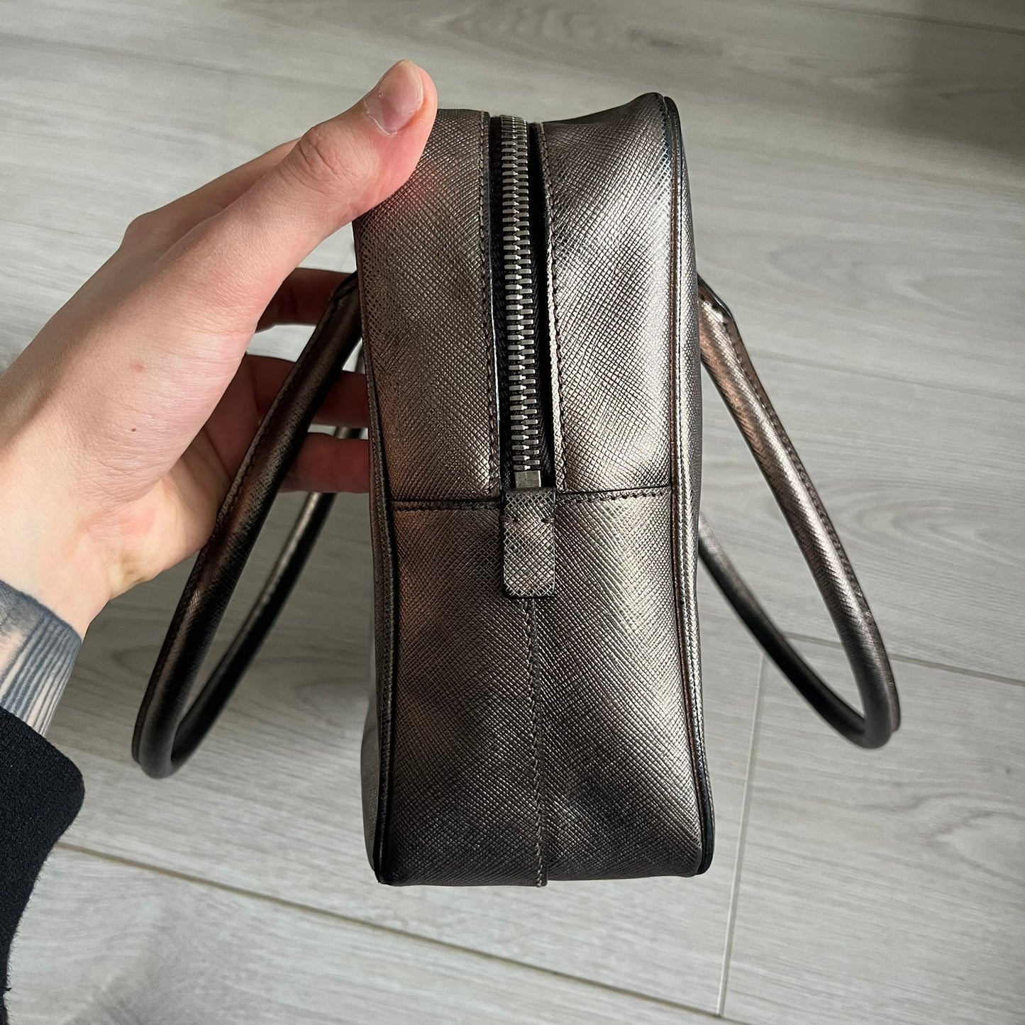 Vintage Prada Metallic Saffiano Bauletto Bag crafted from metallic gold saffiano leather embodies vintage elegance and modern luxury. Detailed with gold-tone hardware, dual handles, and original accessories, it’s a testament to Prada’s enduring craftsmanship. A collector’s piece made to shine on any occasion.