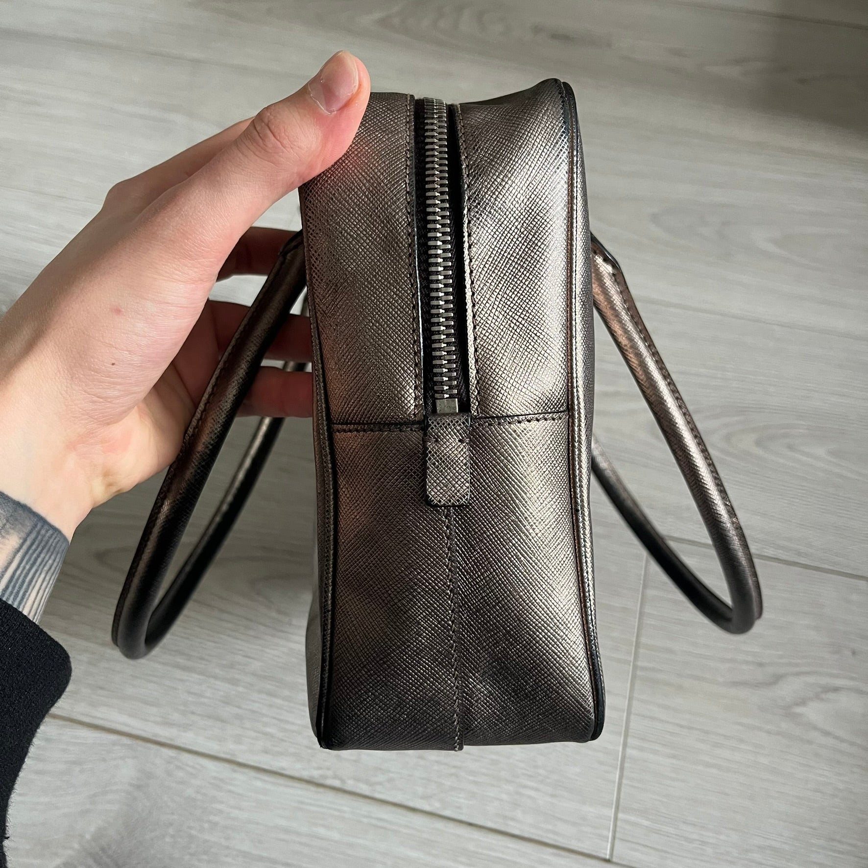 Vintage Prada Metallic Saffiano Bauletto Bag crafted from metallic gold saffiano leather embodies vintage elegance and modern luxury. Detailed with gold-tone hardware, dual handles, and original accessories, it’s a testament to Prada’s enduring craftsmanship. A collector’s piece made to shine on any occasion.