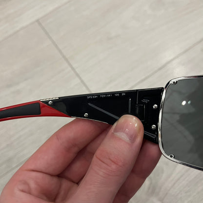 Prada SPS 53H Black/Silver Sunglasses are a vintage wraparound pair featuring a black frame with gunmetal silver accents. The gray lenses are complemented by red details on the arms and visible screws on the front, with Prada branding on the temples. Crafted in Italy from metal and resin, they come complete with the original Prada case.
