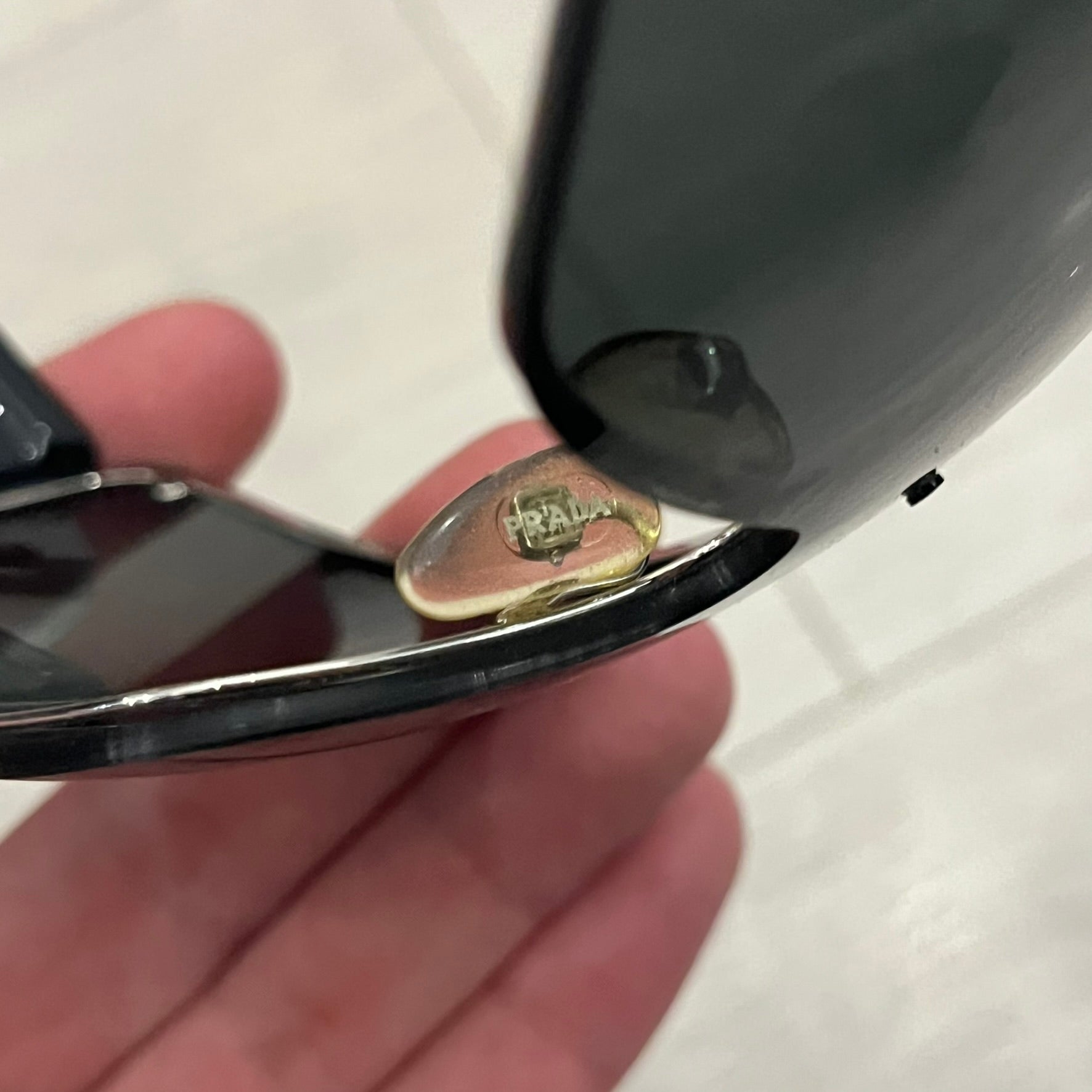 Prada SPS 53H Black/Silver Sunglasses are a vintage wraparound pair featuring a black frame with gunmetal silver accents. The gray lenses are complemented by red details on the arms and visible screws on the front, with Prada branding on the temples. Crafted in Italy from metal and resin, they come complete with the original Prada case.