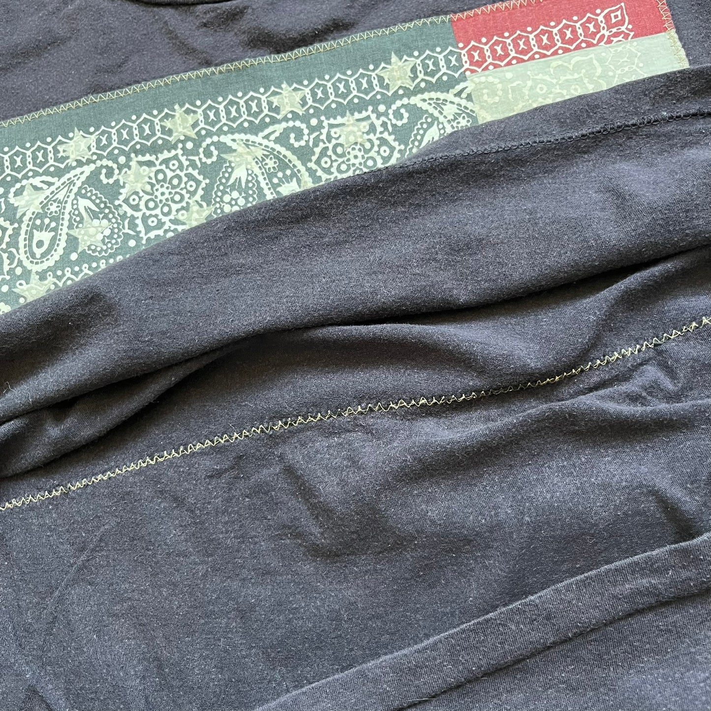 Ralph Lauren 2000s USA Bandana Flag Tee is a navy short-sleeve T-shirt made from 100% cotton. The front features a large USA flag constructed from fabric with a white bandana-style pattern, sewn onto the shirt for a raised effect. This piece comes from the Ralph Lauren Denim &amp; Supply line.