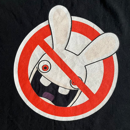 Raving Rabbids - known as “Lapins Crétins” in France - 2010 Tee in black, features a white Rabbid head inside a red circle with a slash, similar to a forbidden symbol. Officially licensed by Ubisoft, it comes with branding tags for collector and fan authenticity.&nbsp;
