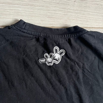 Raving Rabbids - known as “Lapins Crétins” in France - 2010 Tee in black, features a white Rabbid head inside a red circle with a slash, similar to a forbidden symbol. Officially licensed by Ubisoft, it comes with branding tags for collector and fan authenticity.&nbsp;