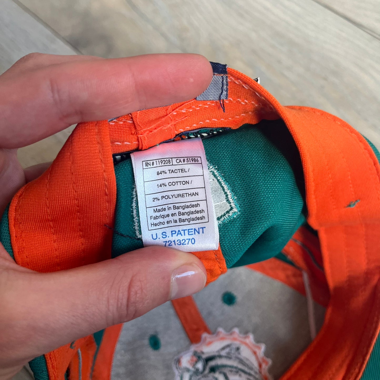 Reebok NFL Miami Dolphins Sideline Baseball Cap is a turquoise baseball cap featuring embroidered Miami Dolphins branding on the front. It includes orange and white accent detailing across the design. The side is finished with a white embroidered Reebok logo, while the back and inside features NFL Equipment tags. The construction uses cotton with a structured fit and a classic adjustable design.