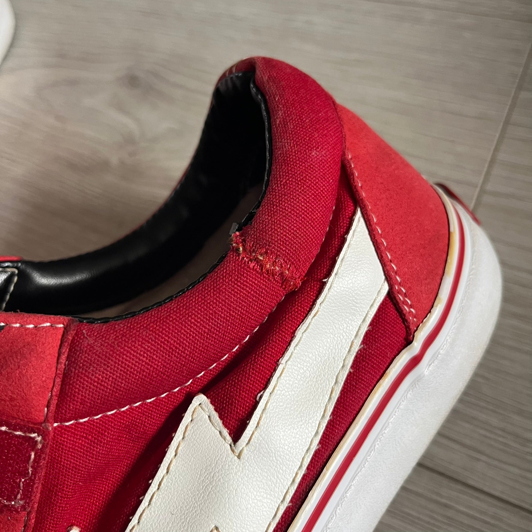 Revenge x Storm Red Strap Sneakers designed by Ian Connor. Featuring a red upper with white leather lightning bolts replacing the traditional Vans stripe. Finished with Velcro strap closures, white midsoles, black outsoles, and the signature “Revenge x Storm” branding in red on the sole.