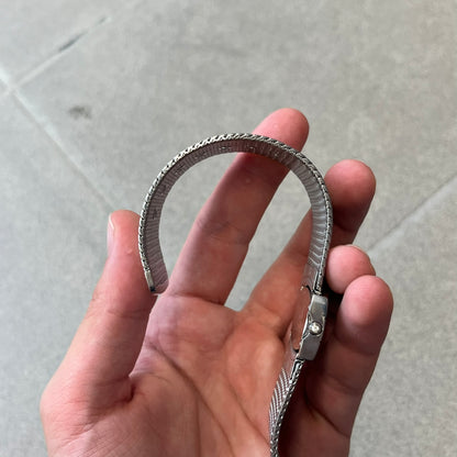 Roberto Cavalli 2000's Ellisse Analog Watch features a curved silver-tone case with a textured mesh bracelet and adjustable strap. The dial has a pearlescent finish that changes slightly depending on the angle, with no hour numbers and a small Roberto Cavalli logo at the bottom.
