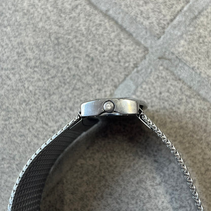 Roberto Cavalli 2000's Ellisse Analog Watch features a curved silver-tone case with a textured mesh bracelet and adjustable strap. The dial has a pearlescent finish that changes slightly depending on the angle, with no hour numbers and a small Roberto Cavalli logo at the bottom.
