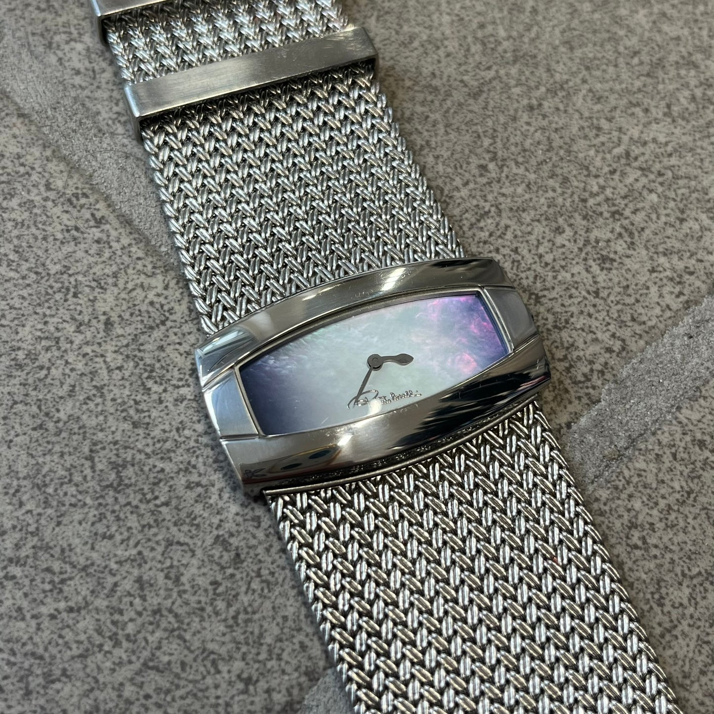 Roberto Cavalli 2000's Ellisse Analog Watch features a curved silver-tone case with a textured mesh bracelet and adjustable strap. The dial has a pearlescent finish that changes slightly depending on the angle, with no hour numbers and a small Roberto Cavalli logo at the bottom.

