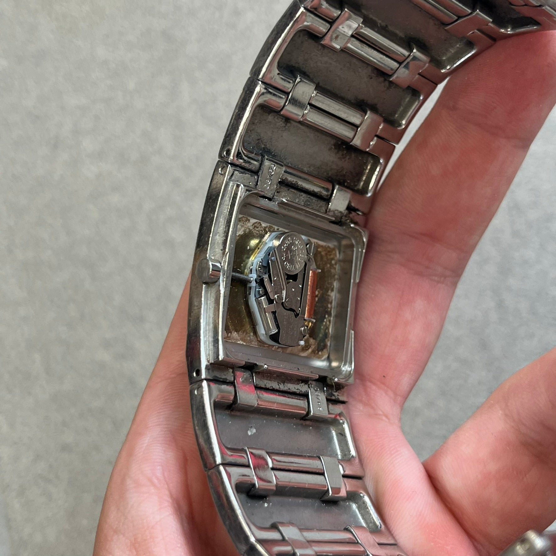  Roberto Cavalli 2000s Silver Croco Analog Watch features a sleek stainless steel design with a case that matches the width of the bracelet for a seamless look. The bracelet is made from silver-tone square links with irregular raised crocodile-inspired texture details. The minimalist white dial has no hour numerals, only the Roberto Cavalli branding.