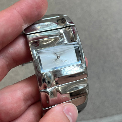  Roberto Cavalli 2000s Silver Croco Analog Watch features a sleek stainless steel design with a case that matches the width of the bracelet for a seamless look. The bracelet is made from silver-tone square links with irregular raised crocodile-inspired texture details. The minimalist white dial has no hour numerals, only the Roberto Cavalli branding.