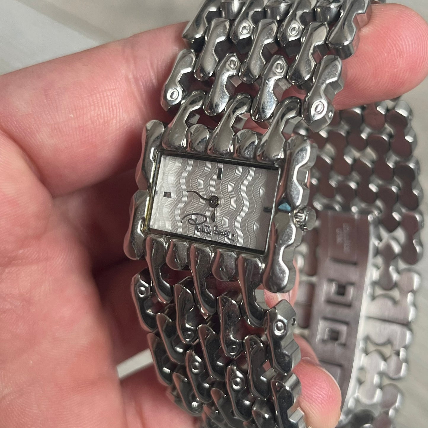 Roberto Cavalli Bones Steel Oryza Analog Watch R7253124015 is a stainless steel analog watch featuring a silver-tone case and integrated bracelet designed with bone-shaped link elements. The dial is aligned with the width of the bracelet, creating a continuous one-piece construction, and includes Cavalli-designed hands. This model uses a quartz movement.