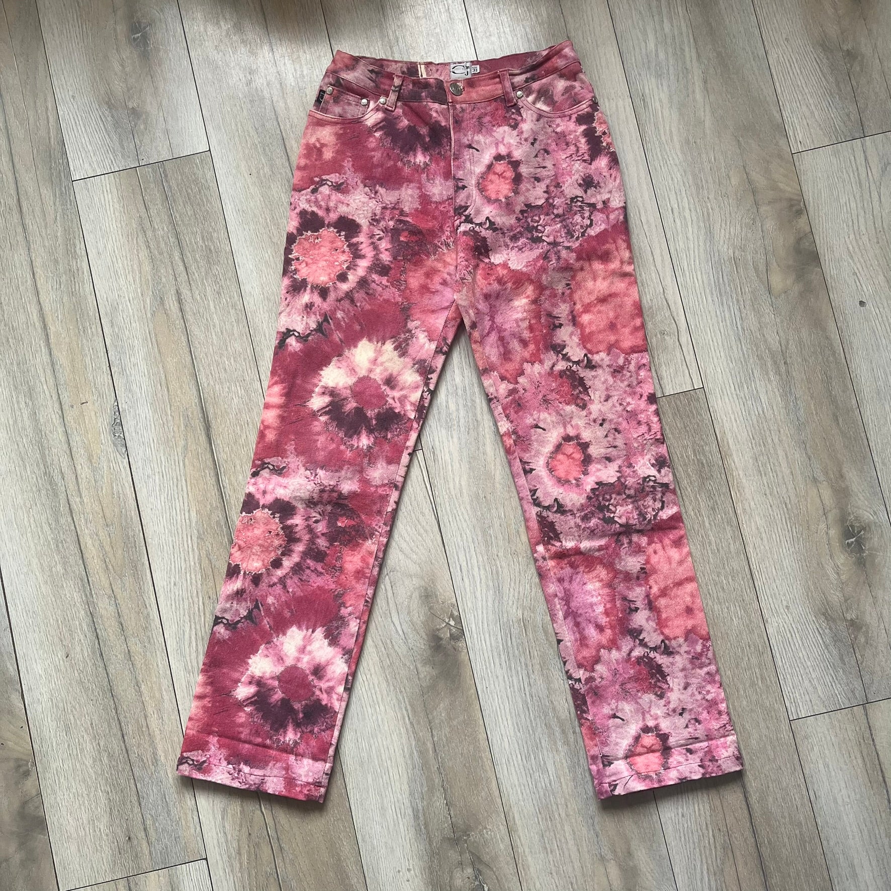 Roberto Cavalli Pink Floral 2000’s Jeans are made in Italy from 98% cotton and 2% elastane. The jeans feature an all-over floral print in multiple shades of pink, ranging from light to dark, with a hand-painted effect across the fabric. Details include branded buttons, a leather logo tab at the back, and classic five-pocket construction with two front and two back pockets.