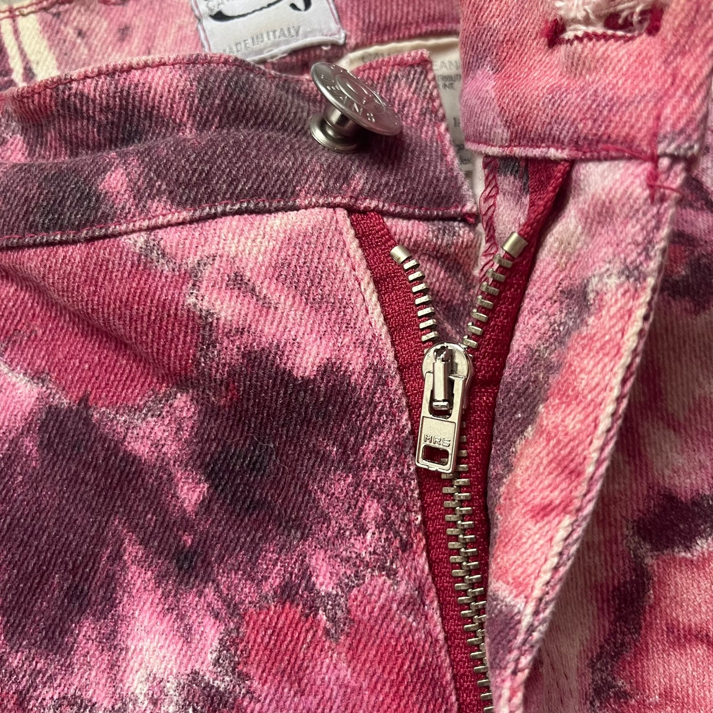 Roberto Cavalli Pink Floral 2000’s Jeans are made in Italy from 98% cotton and 2% elastane. The jeans feature an all-over floral print in multiple shades of pink, ranging from light to dark, with a hand-painted effect across the fabric. Details include branded buttons, a leather logo tab at the back, and classic five-pocket construction with two front and two back pockets.