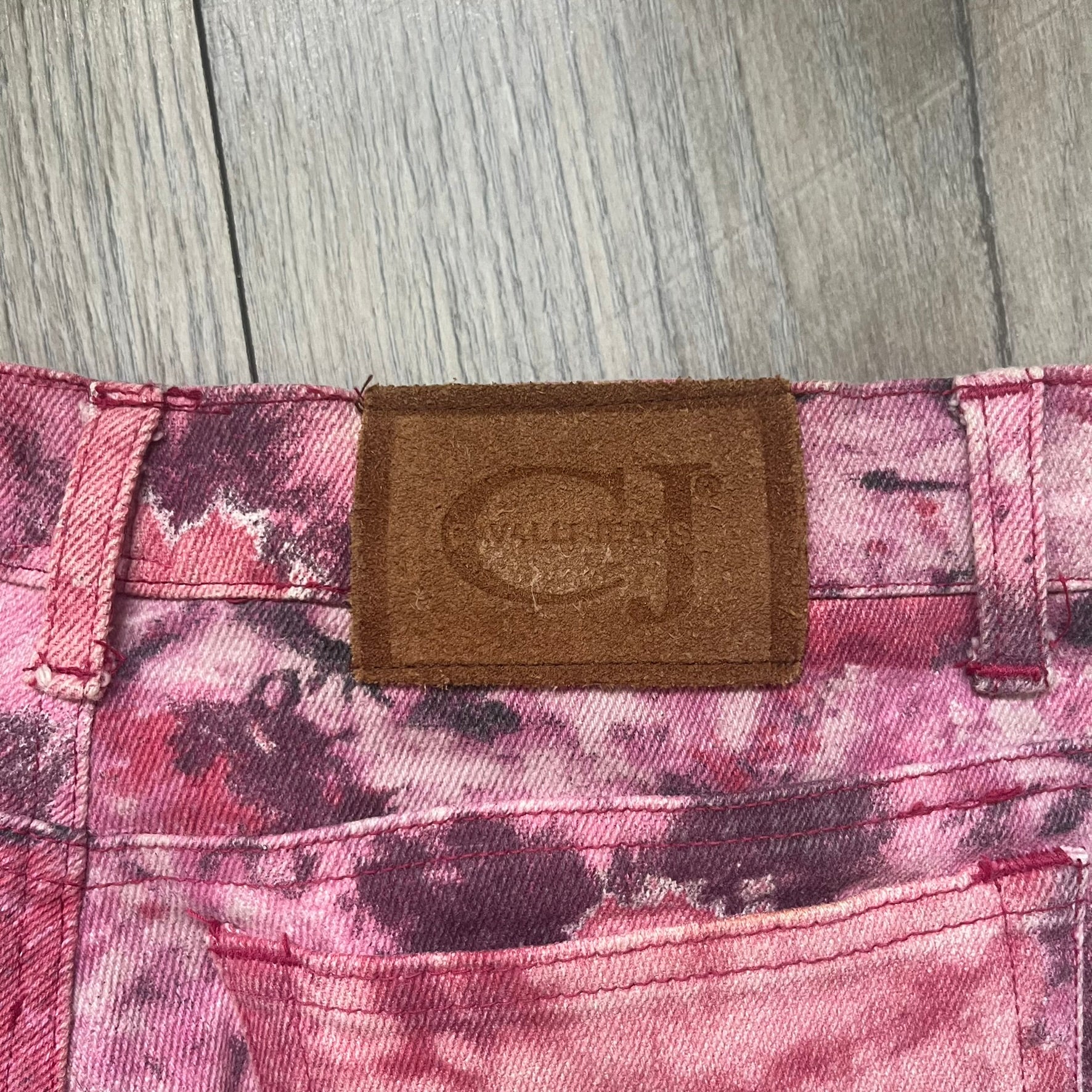 Roberto Cavalli Pink Floral 2000’s Jeans are made in Italy from 98% cotton and 2% elastane. The jeans feature an all-over floral print in multiple shades of pink, ranging from light to dark, with a hand-painted effect across the fabric. Details include branded buttons, a leather logo tab at the back, and classic five-pocket construction with two front and two back pockets.