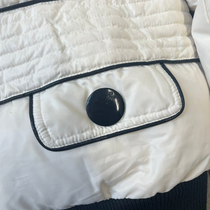 Rocawear 2000’s White Bomber Jacket is a white women’s bomber jacket with black details and a black Rocawear “R” logo on the left chest. It has two front pockets with oversized black buttons and a branded zipper, and a Rocawear logo runs across the upper back.