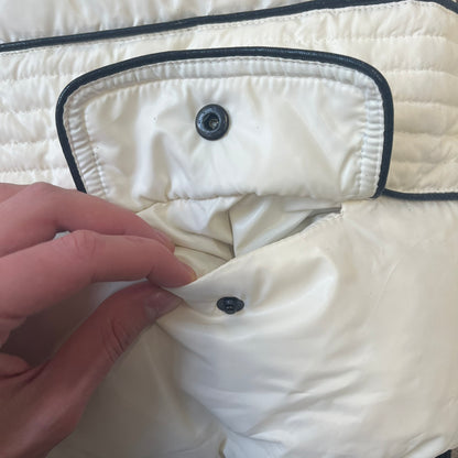 Rocawear 2000’s White Bomber Jacket is a white women’s bomber jacket with black details and a black Rocawear “R” logo on the left chest. It has two front pockets with oversized black buttons and a branded zipper, and a Rocawear logo runs across the upper back.