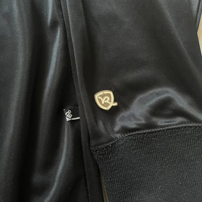 Vintage Rocawear black track jacket featuring a small embroidered chest logo and big white branding across the back. Silver zipper and wrist emblem add refined details to this early-2000s streetwear classic.