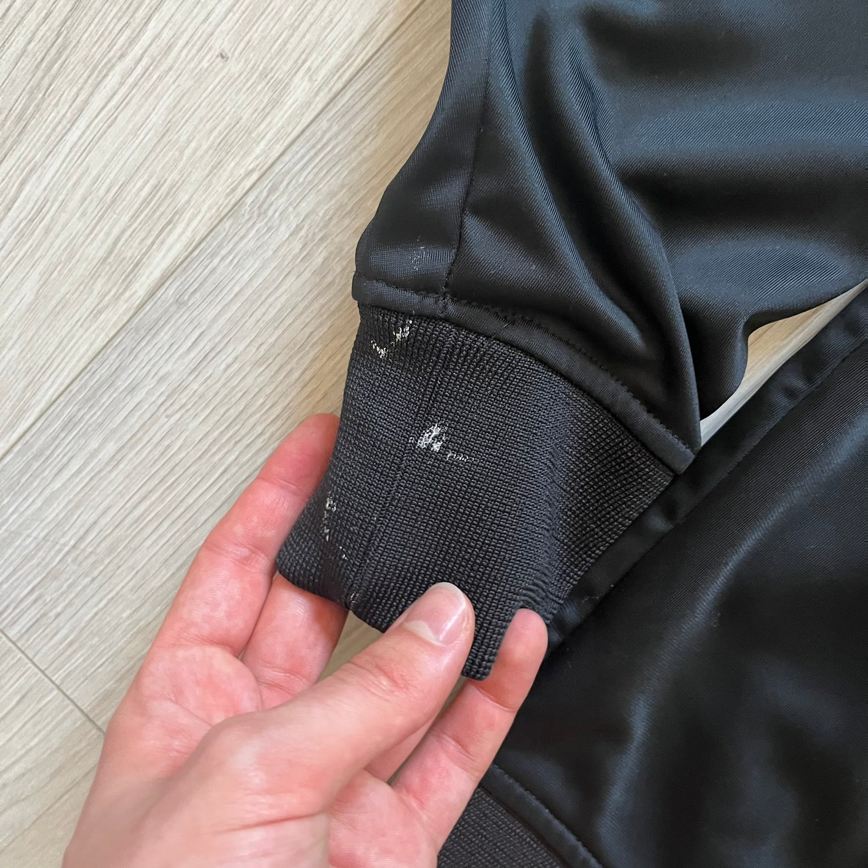 Rocawear black track jacket in size large, designed with a small embroidered logo on the chest and a large white logo across the back. A silver emblem near the wrist and a detailed silver zipper add distinctive touches. A sleek early 2000s streetwear piece.