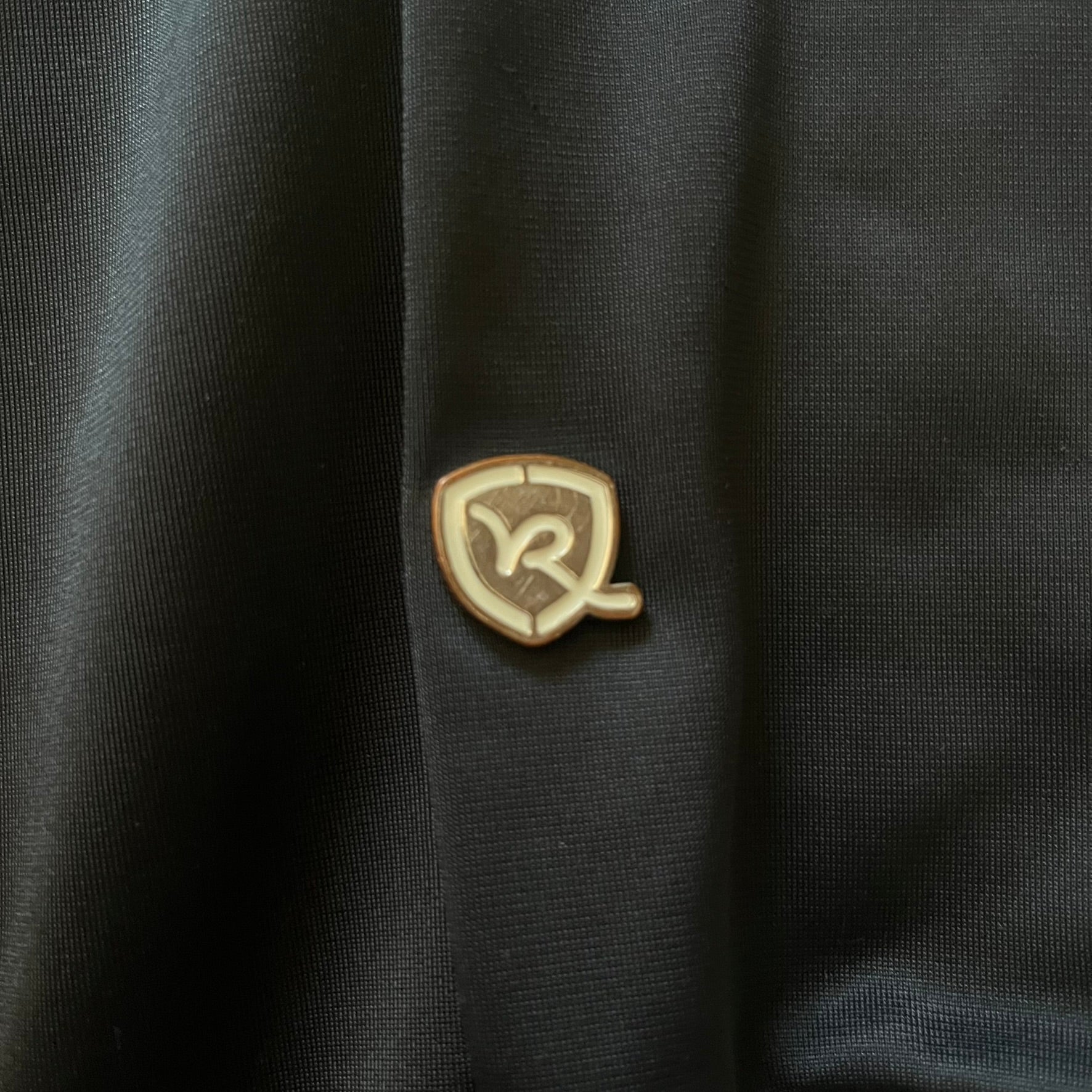 Rocawear black track jacket in size large, designed with a small embroidered logo on the chest and a large white logo across the back. A silver emblem near the wrist and a detailed silver zipper add distinctive touches. A sleek early 2000s streetwear piece.