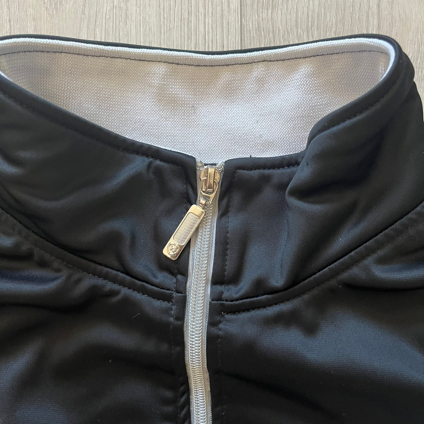 Rocawear black track jacket in size large, designed with a small embroidered logo on the chest and a large white logo across the back. A silver emblem near the wrist and a detailed silver zipper add distinctive touches. A sleek early 2000s streetwear piece.