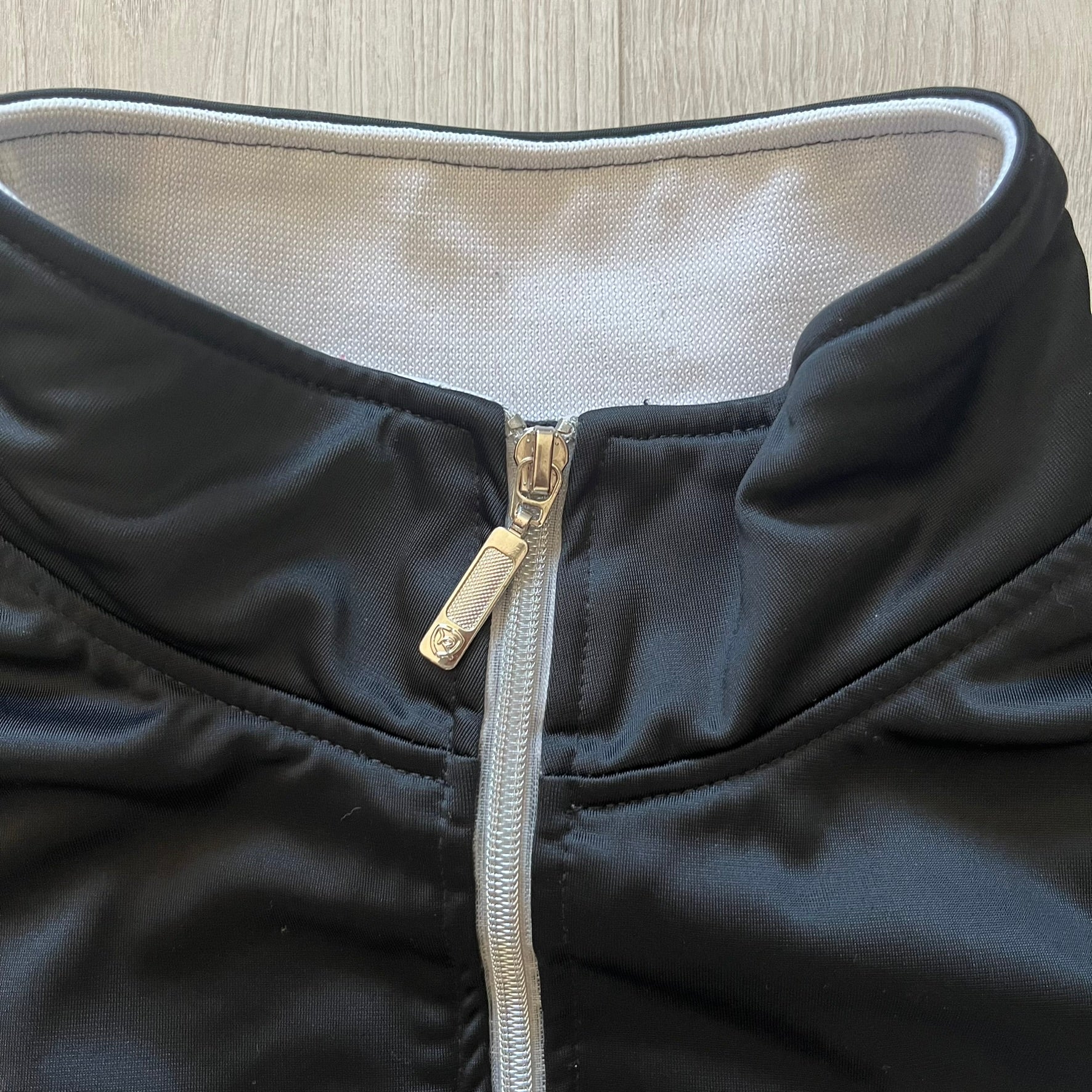 Rocawear black track jacket in size large, designed with a small embroidered logo on the chest and a large white logo across the back. A silver emblem near the wrist and a detailed silver zipper add distinctive touches. A sleek early 2000s streetwear piece.