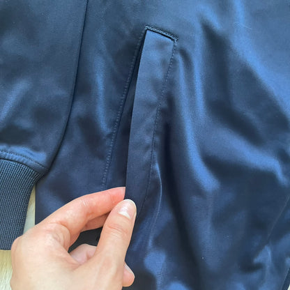 Rocawear Dark Navy Vintage Track Jacket, featuring a small embroidered logo on the chest and a large white logo across the back, finished with a silver emblem near the wrist and a detailed silver zipper.