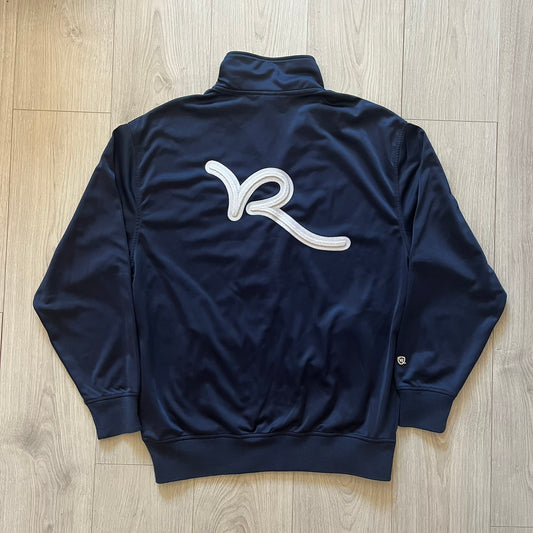 Rocawear Dark Navy Vintage Track Jacket, featuring a small embroidered logo on the chest and a large white logo across the back, finished with a silver emblem near the wrist and a detailed silver zipper.