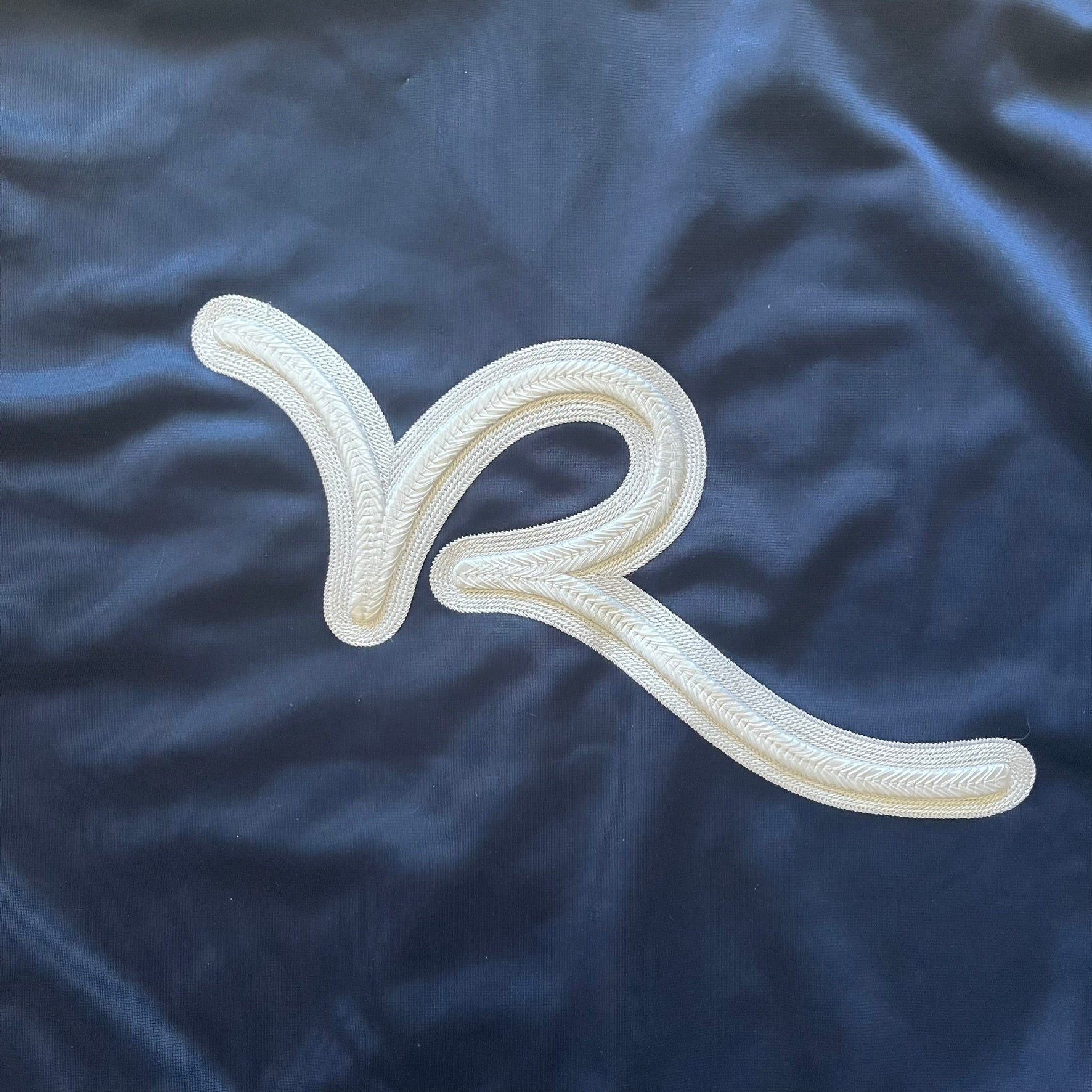 Rocawear Dark Navy Vintage Track Jacket, featuring a small embroidered logo on the chest and a large white logo across the back, finished with a silver emblem near the wrist and a detailed silver zipper.