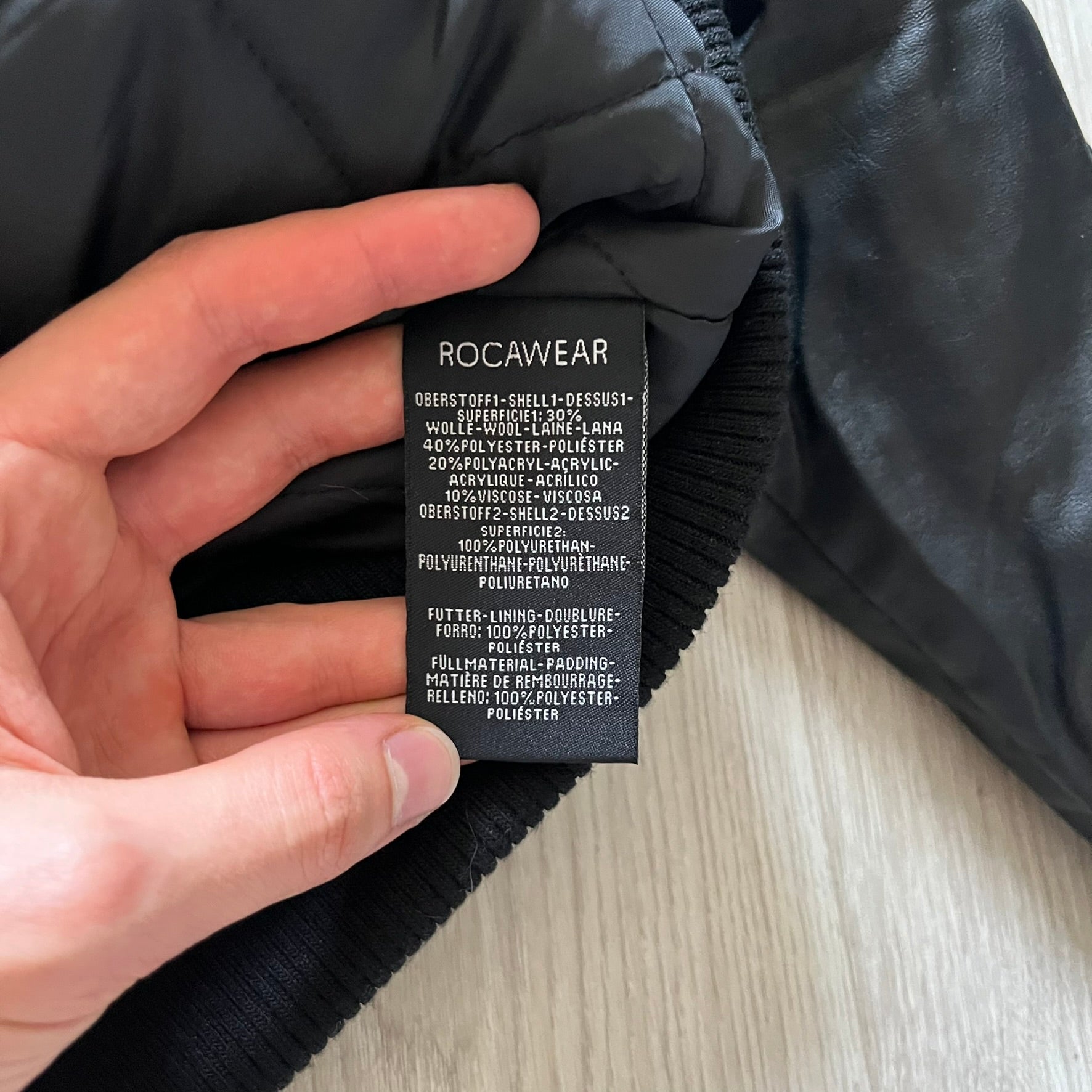 Rocawear black bomber jacket detailed with multiple statement patches, including “R” and “W” on the shoulders, a Rocawear logo with a “4” on the chest, and a large text logo across the back. Crafted with great detailing, it reflects the brand’s early 2000s streetwear identity.