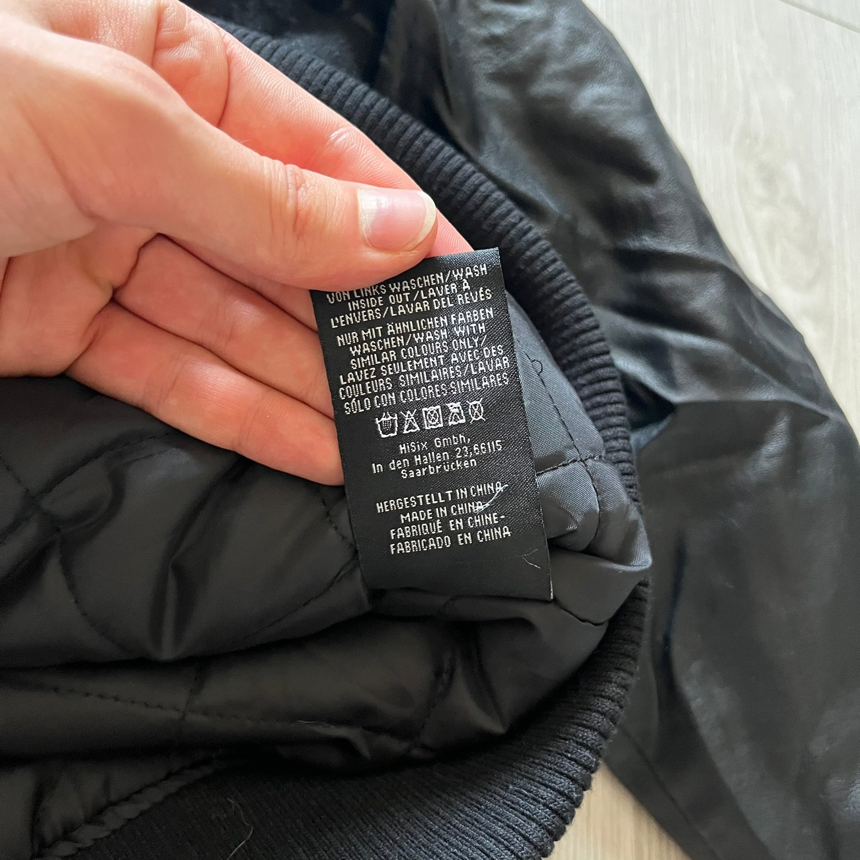 Rocawear black bomber jacket detailed with multiple statement patches, including “R” and “W” on the shoulders, a Rocawear logo with a “4” on the chest, and a large text logo across the back. Crafted with great detailing, it reflects the brand’s early 2000s streetwear identity.