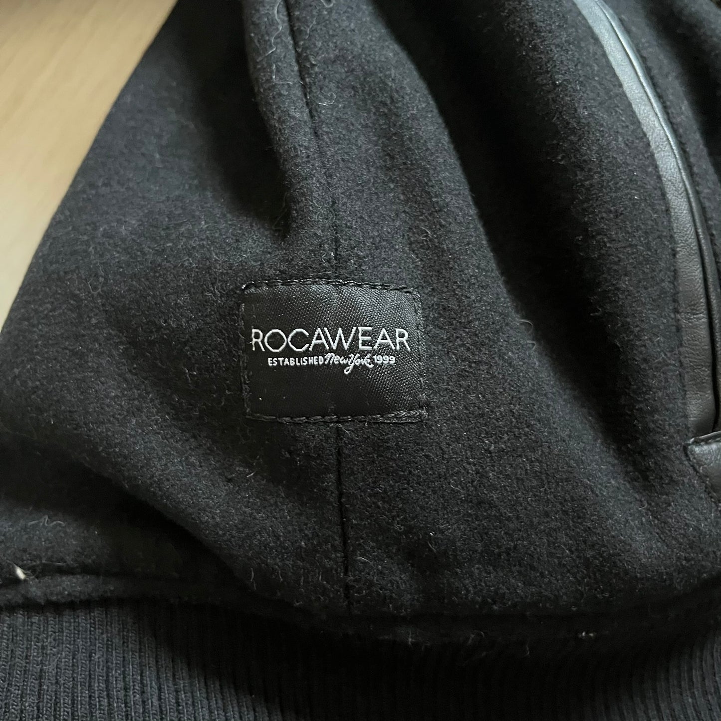 Rocawear black bomber jacket detailed with multiple statement patches, including “R” and “W” on the shoulders, a Rocawear logo with a “4” on the chest, and a large text logo across the back. Crafted with great detailing, it reflects the brand’s early 2000s streetwear identity.