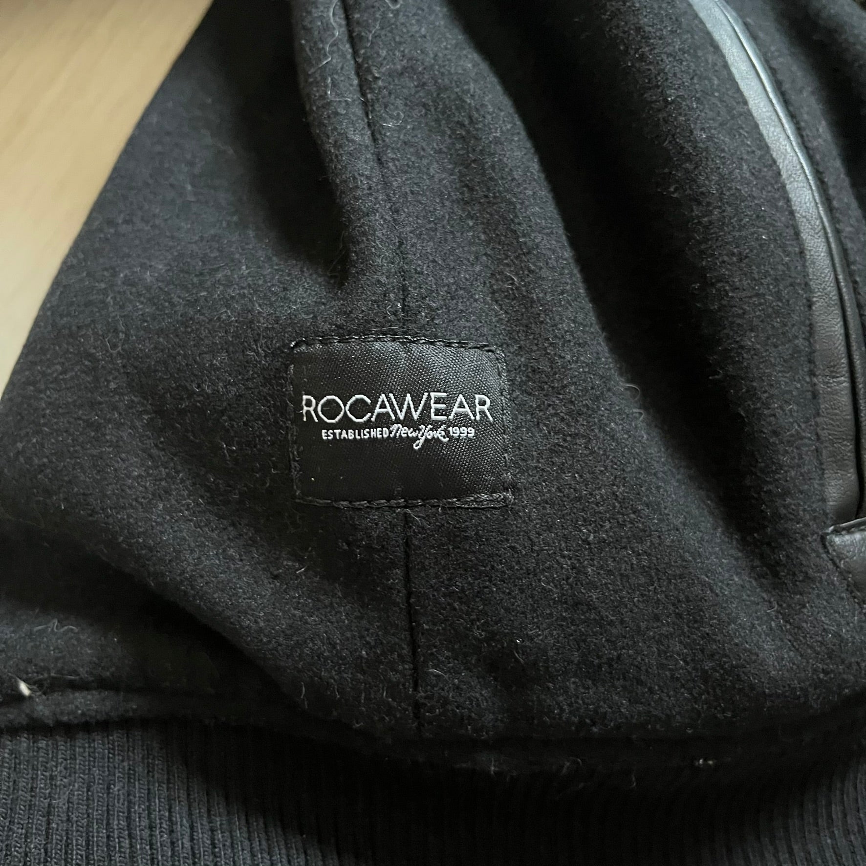 Rocawear black bomber jacket detailed with multiple statement patches, including “R” and “W” on the shoulders, a Rocawear logo with a “4” on the chest, and a large text logo across the back. Crafted with great detailing, it reflects the brand’s early 2000s streetwear identity.