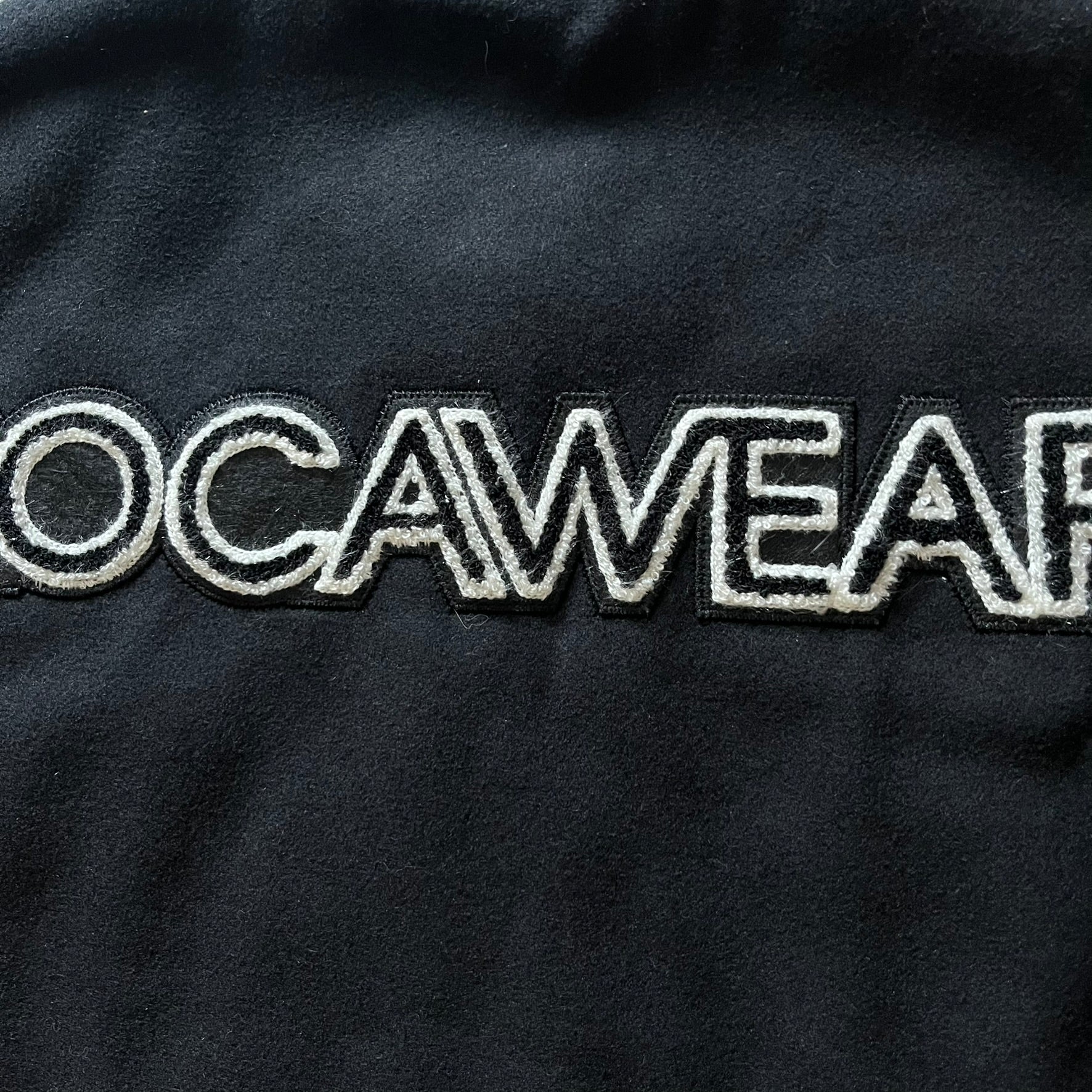 Rocawear black bomber jacket detailed with multiple statement patches, including “R” and “W” on the shoulders, a Rocawear logo with a “4” on the chest, and a large text logo across the back. Crafted with great detailing, it reflects the brand’s early 2000s streetwear identity.