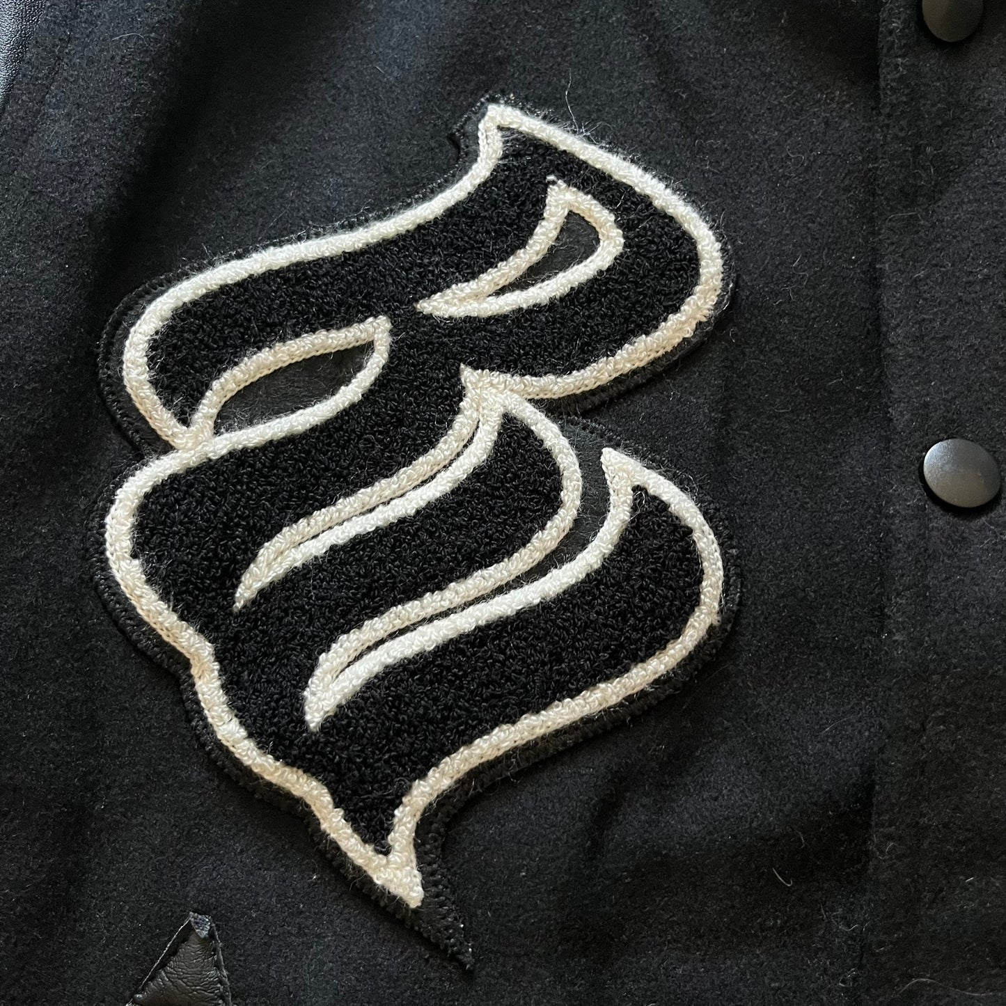 Rocawear black bomber jacket detailed with multiple statement patches, including “R” and “W” on the shoulders, a Rocawear logo with a “4” on the chest, and a large text logo across the back. Crafted with great detailing, it reflects the brand’s early 2000s streetwear identity.