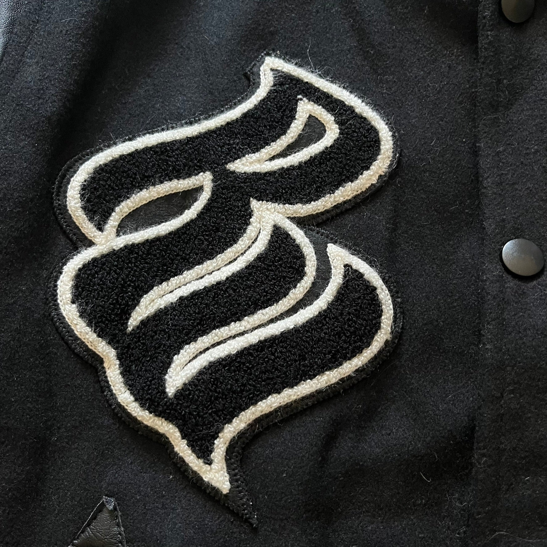 Rocawear black bomber jacket detailed with multiple statement patches, including “R” and “W” on the shoulders, a Rocawear logo with a “4” on the chest, and a large text logo across the back. Crafted with great detailing, it reflects the brand’s early 2000s streetwear identity.
