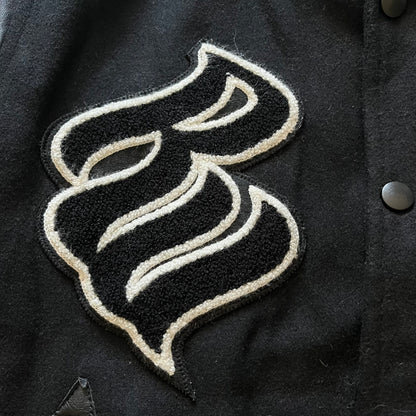 Rocawear black bomber jacket detailed with multiple statement patches, including “R” and “W” on the shoulders, a Rocawear logo with a “4” on the chest, and a large text logo across the back. Crafted with great detailing, it reflects the brand’s early 2000s streetwear identity.