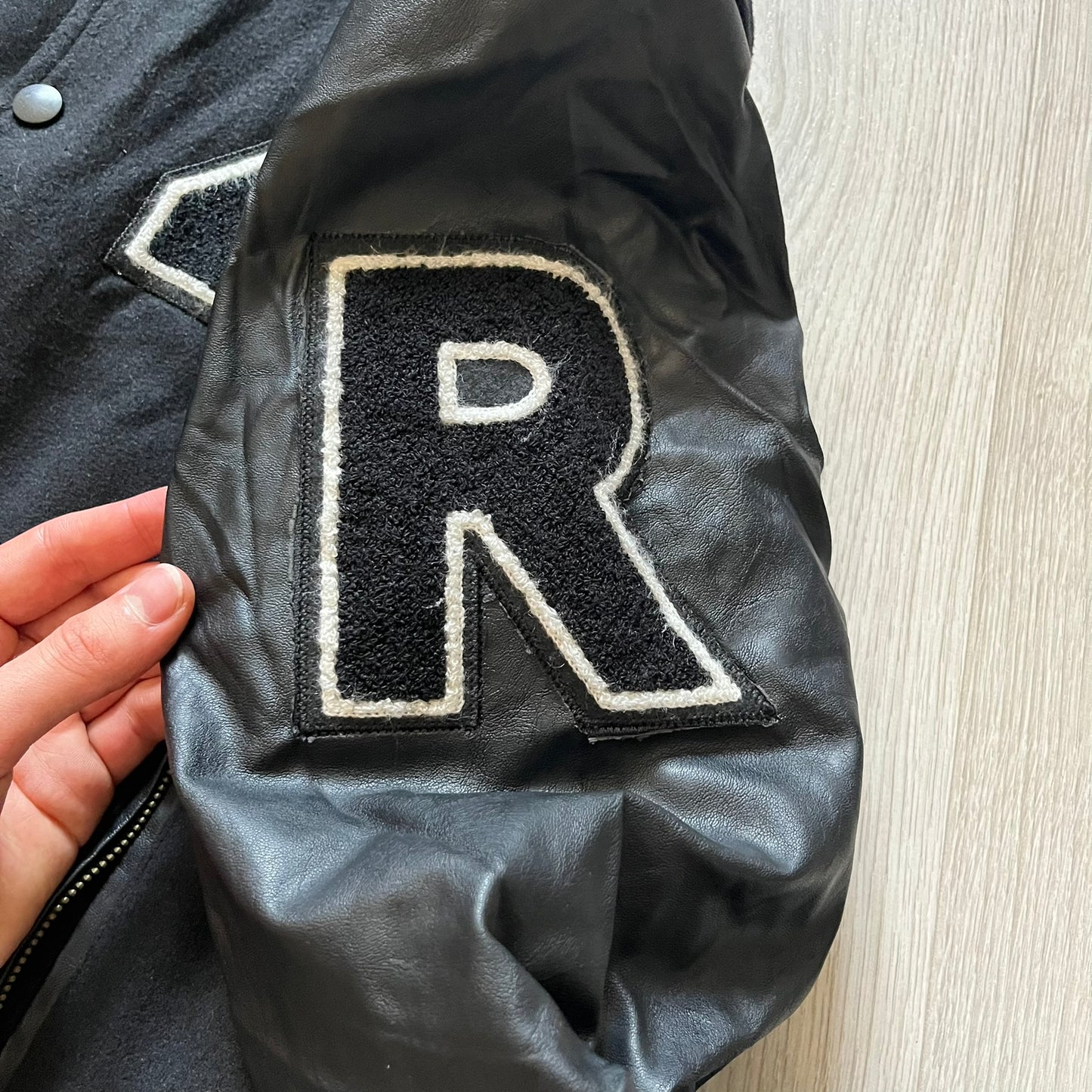 Rocawear black bomber jacket detailed with multiple statement patches, including “R” and “W” on the shoulders, a Rocawear logo with a “4” on the chest, and a large text logo across the back. Crafted with great detailing, it reflects the brand’s early 2000s streetwear identity.