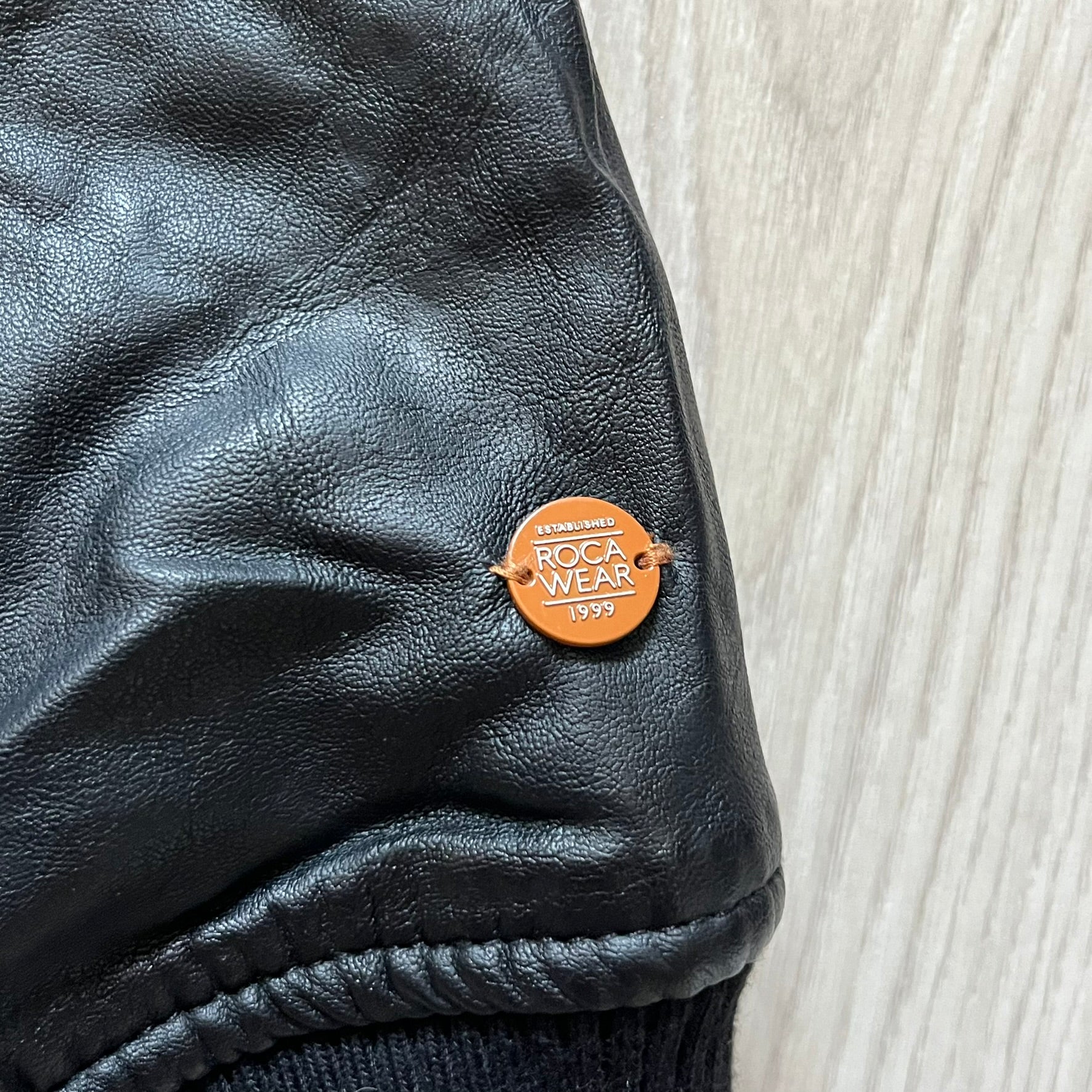 Rocawear black bomber jacket detailed with multiple statement patches, including “R” and “W” on the shoulders, a Rocawear logo with a “4” on the chest, and a large text logo across the back. Crafted with great detailing, it reflects the brand’s early 2000s streetwear identity.